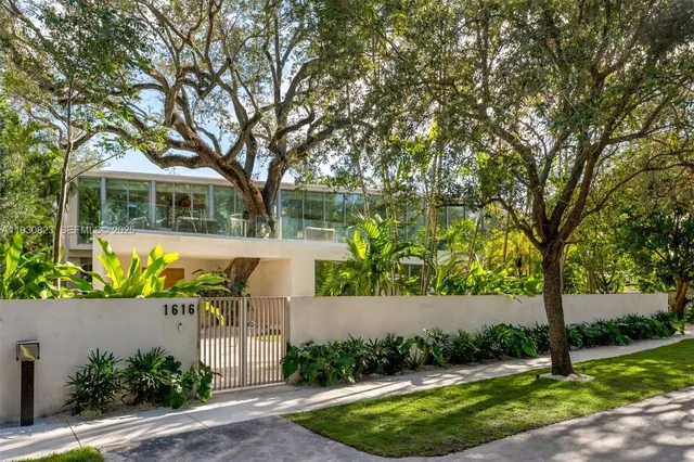 a front view of a house with garden and trees