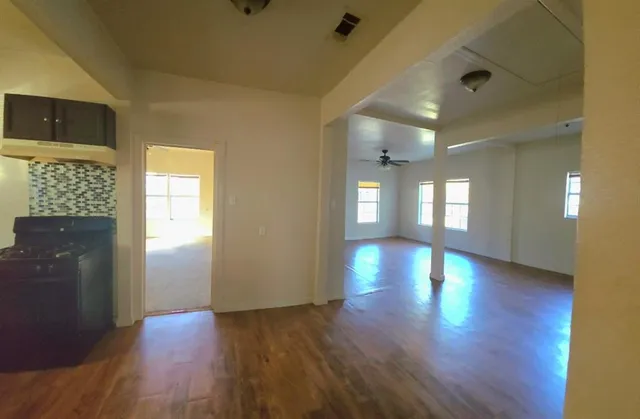 a view of an empty room with window and wooden floor
