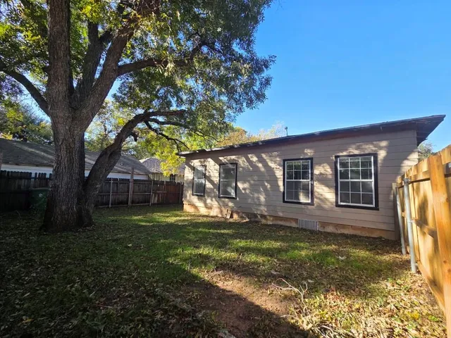 a view of a yard in front of a house with large tree