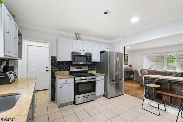 a kitchen with stainless steel appliances granite countertop a refrigerator a stove a sink a dining table and chairs