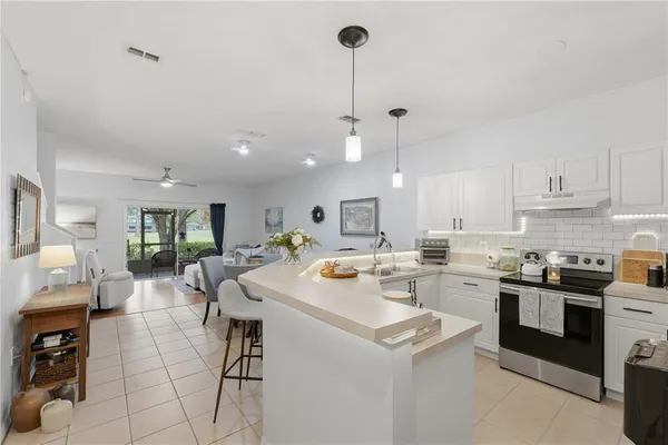 a kitchen with a stove a sink a kitchen island with chairs and white cabinets
