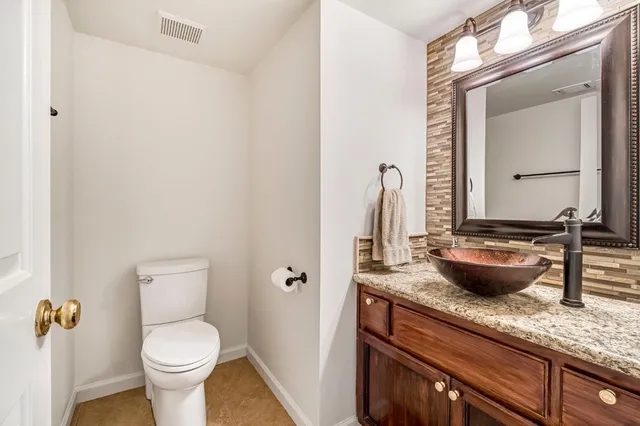 a bathroom with a granite countertop sink a toilet and a mirror