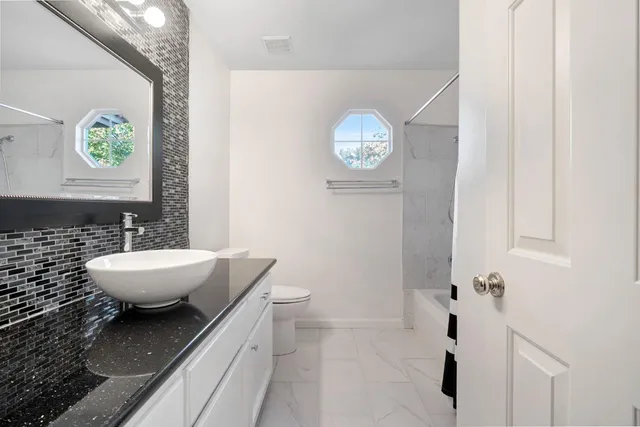 a bathroom with a granite countertop sink and a mirror