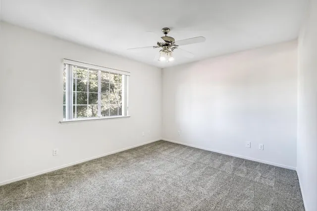 an empty room with a window and a fan