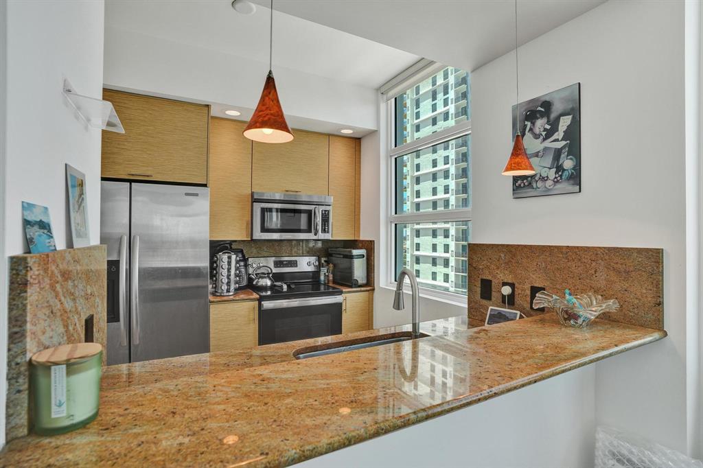 315 Northeast 3rd Avenue, Unit 1201 Fort Lauderdale, FL 33301 - Photo 5 of 49 a kitchen with stainless steel appliances granite countertop a refrigerator a stove and a sink with wooden floor