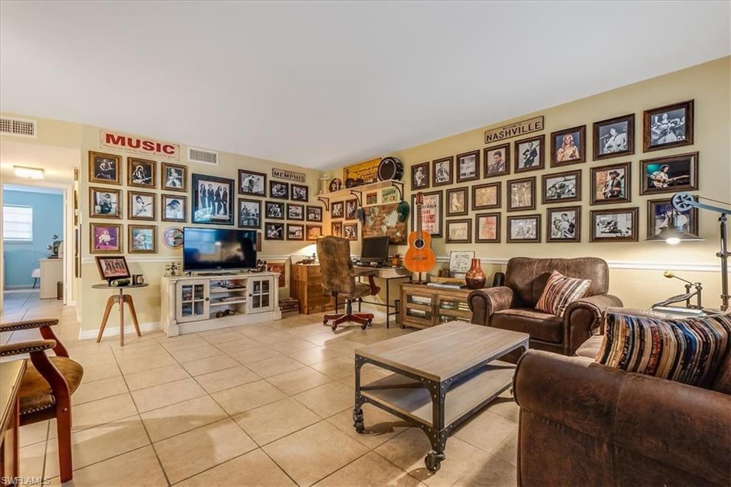 4290 Gulfstream Drive, Unit 4 Naples, FL 34112 - Photo 12 of 20 a living room with furniture a bookshelf and a flat screen tv
