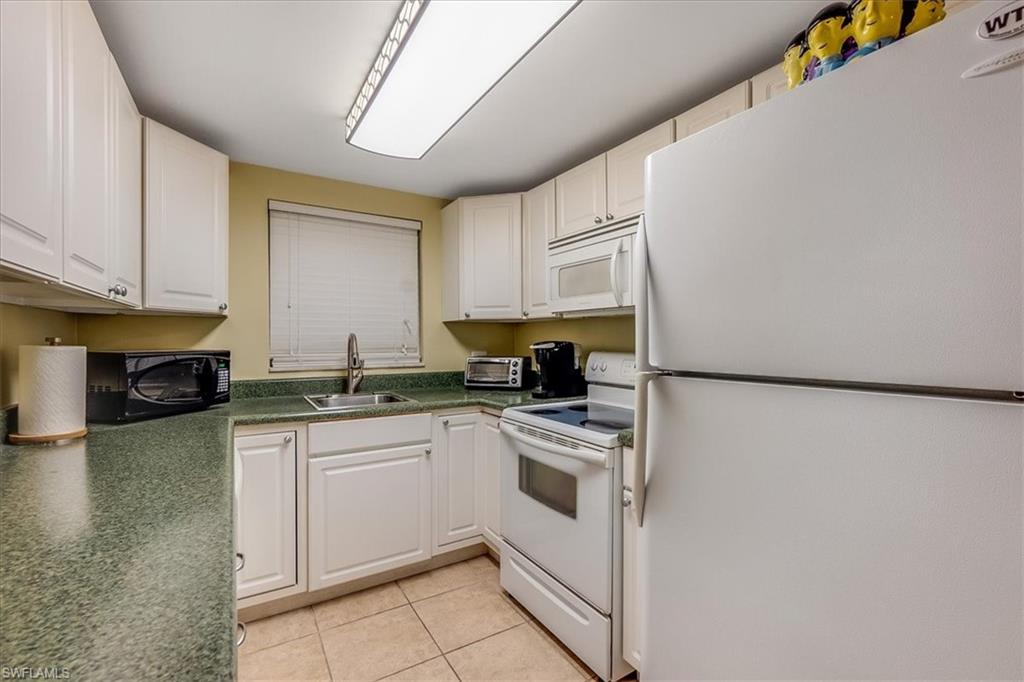 4290 Gulfstream Drive, Unit 4 Naples, FL 34112 - Photo 6 of 20 a kitchen with a sink a stove top oven and white cabinets