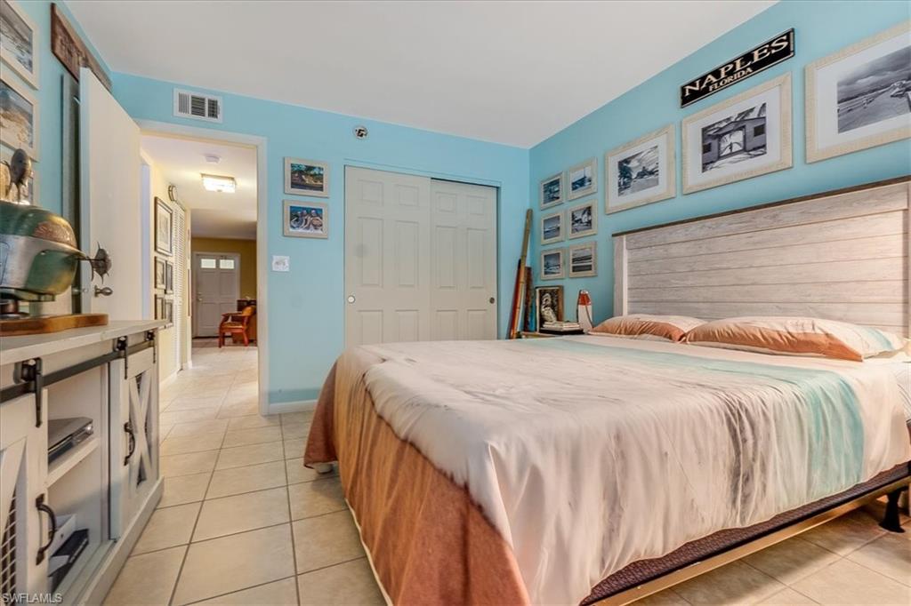 4290 Gulfstream Drive, Unit 4 Naples, FL 34112 - Photo 9 of 20 a bedroom with a large bed and a chandelier