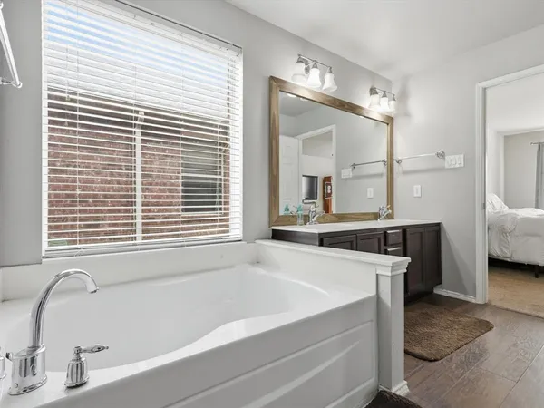 a bathroom with a tub a sink and a large mirror
