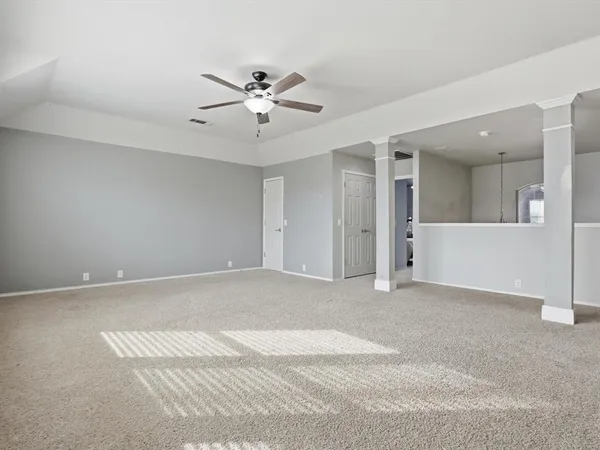 a view of an empty room with chandelier fan