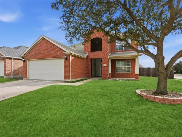 a front view of a house with a yard and large tree