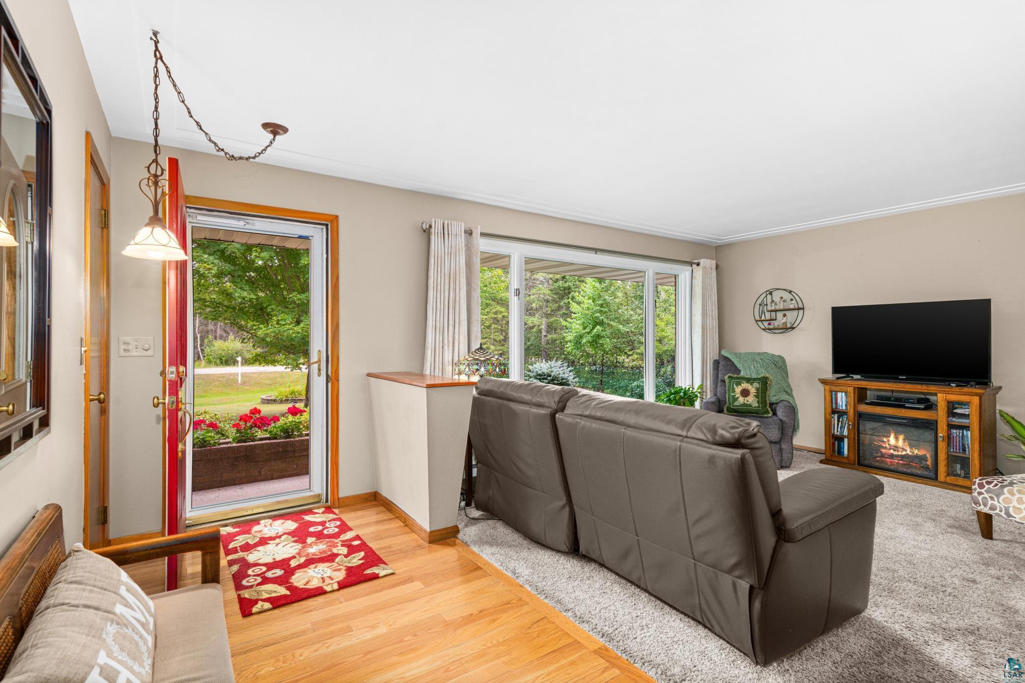 3727 Stebner Road Hermantown, MN 55811 - Photo 6 of 41 Hardwood flooring at entry, crown molding, large sliding glass door, and a built-in media console with an electric fireplace