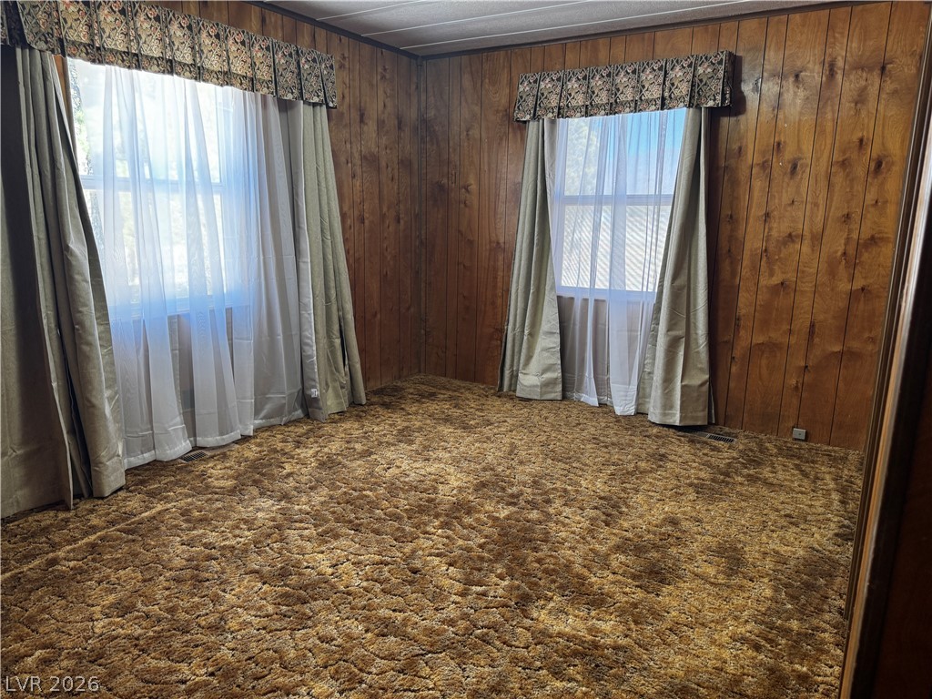 3090 Gally Road Pahrump, NV 89060 - Photo 14 of 20 A cozy bedroom with rich wood paneling and plush, textured carpeting.