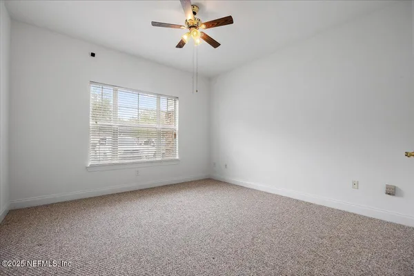 an empty room with windows and fan