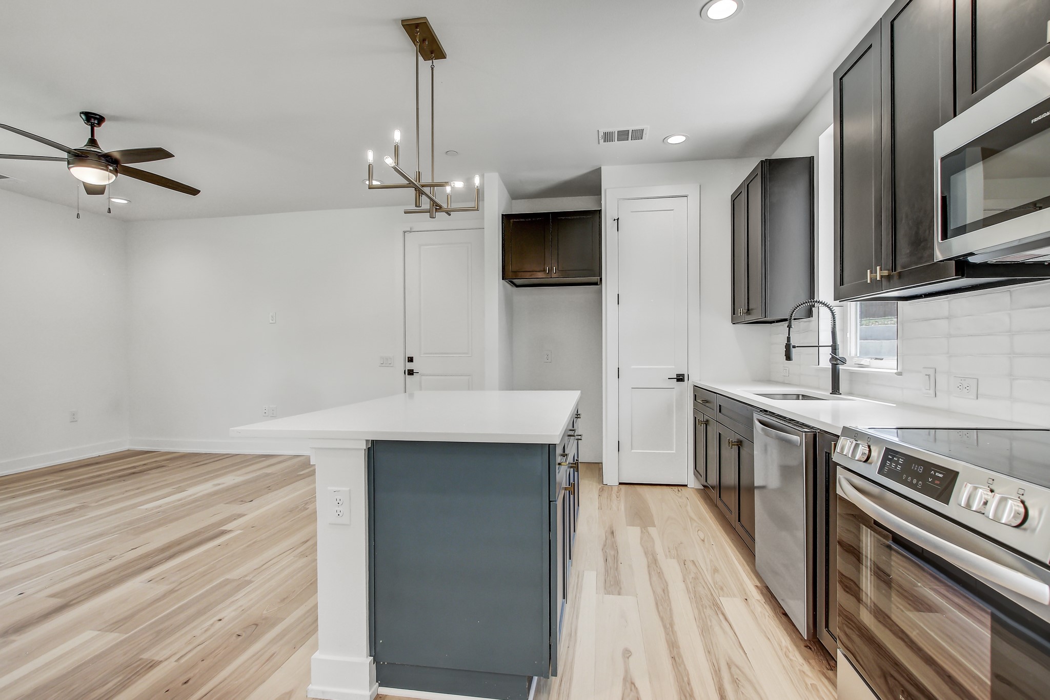 4127 East 12th Street, Unit 4 Austin, TX 78721 - Photo 4 of 32 Kitchen with appliances with stainless steel finishes, a sink, light wood-style floors, recessed lighting, and a kitchen island
