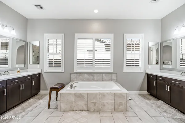 a spacious bathroom with a tub a sink and a large mirror