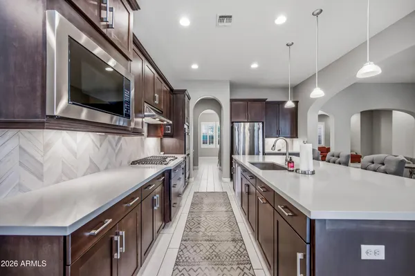 a kitchen with stainless steel appliances granite countertop a stove a sink dishwasher a microwave oven and a dining table with wooden floor