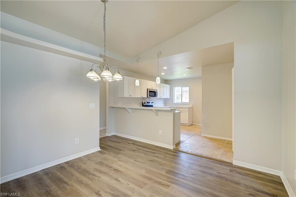 8381 Blackberry Road Fort Myers, FL 33967 - Photo 7 of 36 Kitchen with light hardwood / wood-style flooring, kitchen peninsula, white cabinets, and a breakfast bar area