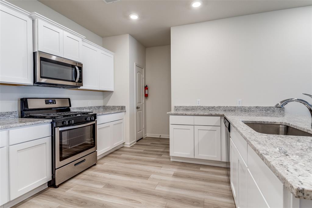 320 Stone Court Princeton, TX 75407 - Photo 2 of 15 a kitchen with granite countertop a sink stove and microwave
