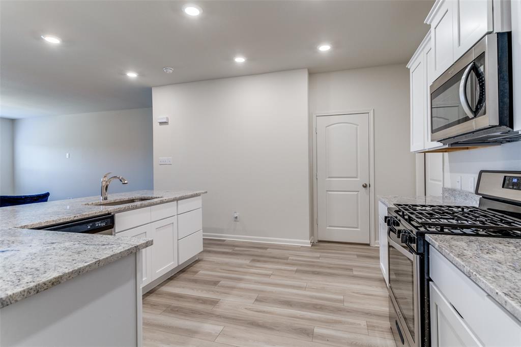 320 Stone Court Princeton, TX 75407 - Photo 4 of 15 a kitchen with granite countertop a sink stainless steel appliances and cabinets