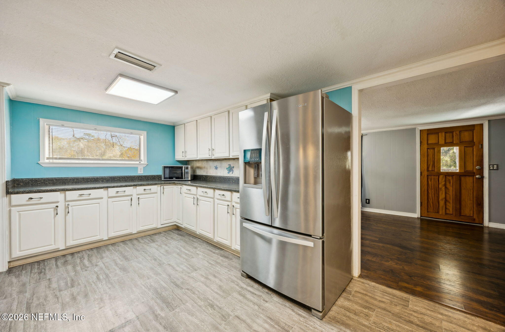 8117 Northwest County Road, Unit 225 Raiford, FL 32083 - Photo 11 of 38 a kitchen with a refrigerator and white cabinets