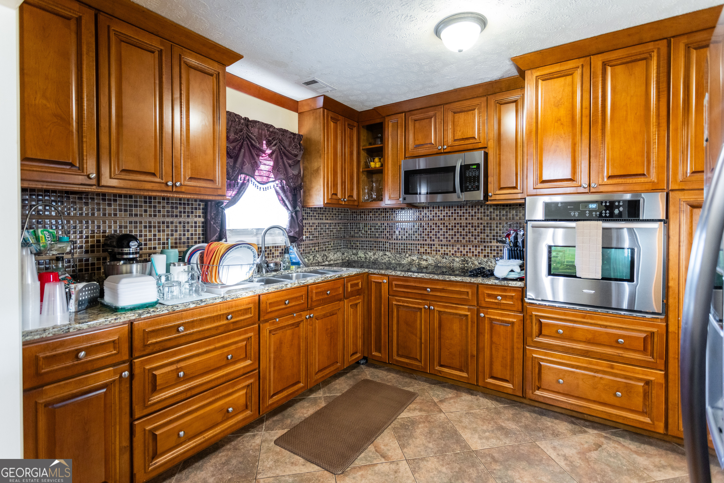 338 Boxwood Street Social Circle, GA 30025 - Photo 11 of 22 a kitchen with granite countertop wooden cabinets stainless steel appliances and a window