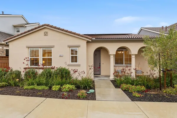a view of a white house with potted plants