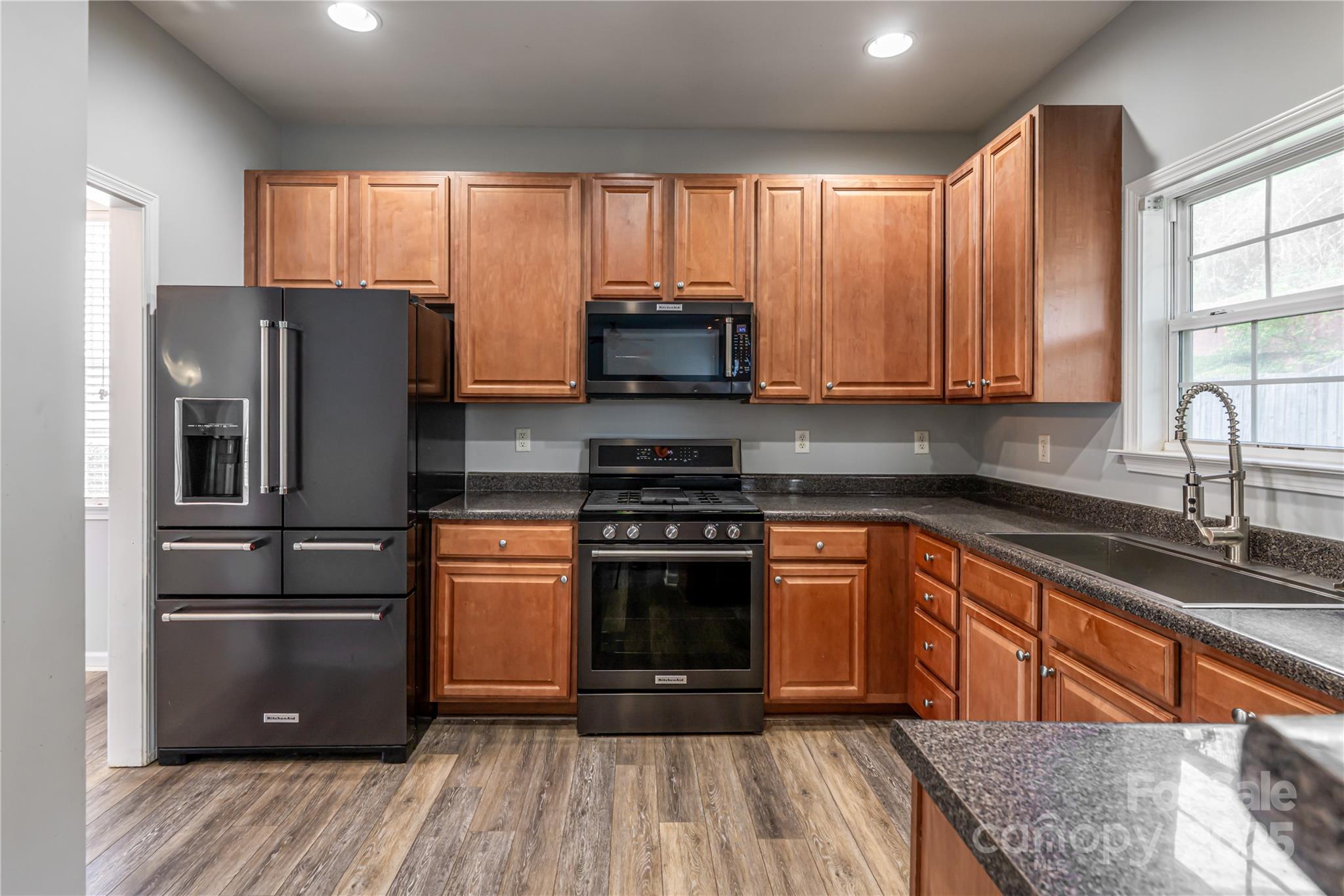 163 Yadkin Road Fletcher, NC 28732 - Photo 17 of 43 a kitchen with granite countertop wooden floors stainless steel appliances and window