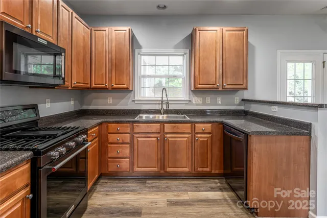 a kitchen with stainless steel appliances granite countertop a stove a sink and a microwave