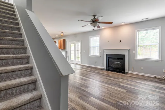 a view of an empty room with wooden floor fireplace and a window