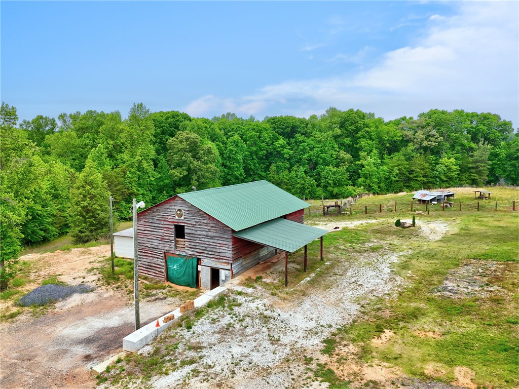 433 Latham Road Easley, SC 29640 - Photo 14 of 50 A rustic barn with a verdant roof sits amidst a sprawling, tree-lined landscape.
