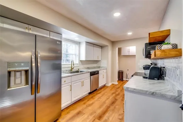 a kitchen with granite countertop a sink stainless steel appliances and cabinets