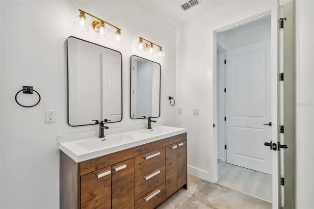 a bathroom with a double vanity sink toilet and mirror