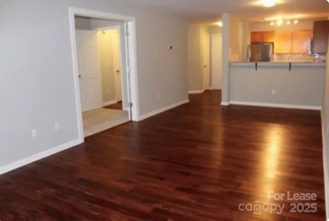 an empty room with wooden floor and a kitchen