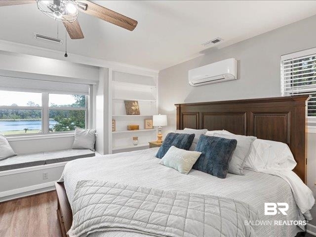 4650 Wiggins Lane Wilmer, AL 36587 - Photo 16 of 66 Bedroom featuring multiple windows, wood finished floors, a ceiling fan, and a wall mounted AC