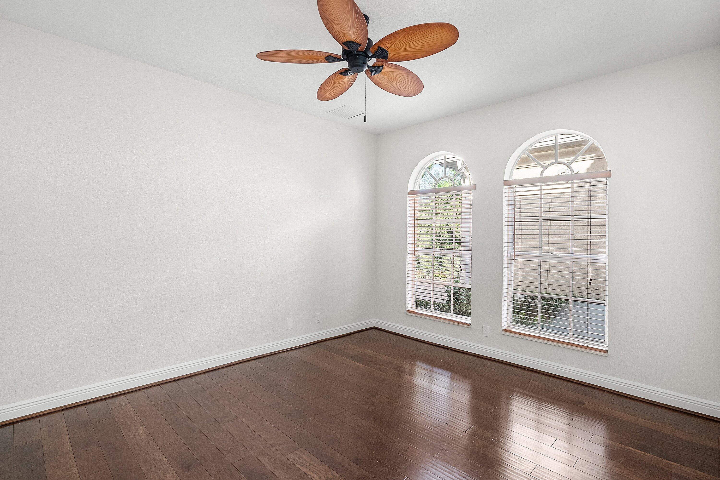 6468 Polo Pointe Way Delray Beach, FL 33484 - Photo 29 of 89 an empty room with wooden floor chandelier fan and windows