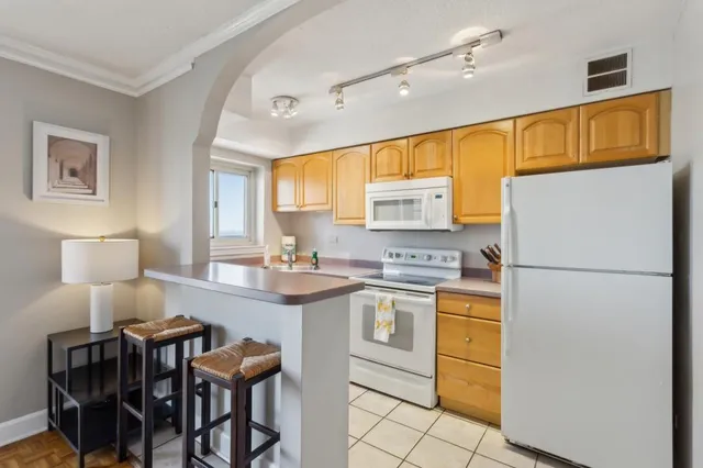 a kitchen with a sink a refrigerator and chairs