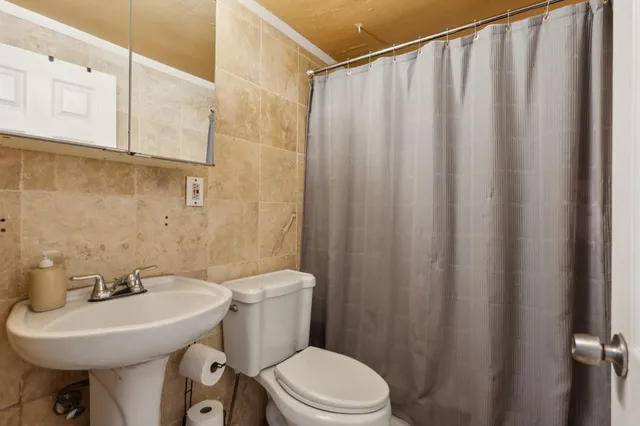 a bathroom with a sink a toilet a mirror and shower curtain