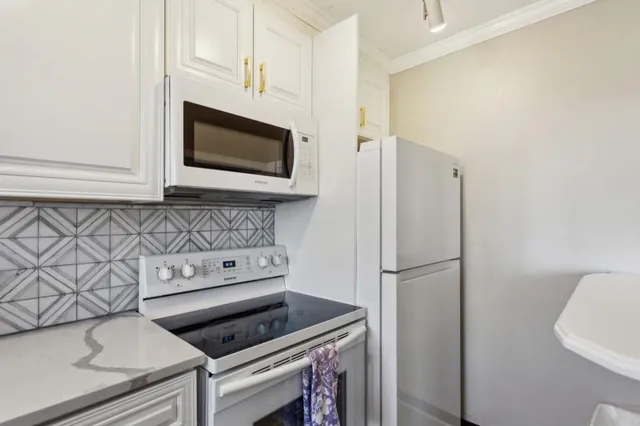 a kitchen with stainless steel appliances white cabinets and a stove top oven