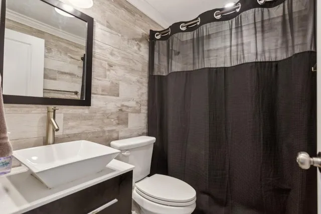 a bathroom with a sink a toilet a mirror and shower curtain