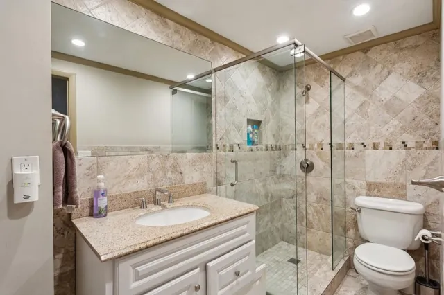a bathroom with a granite countertop sink a toilet and shower