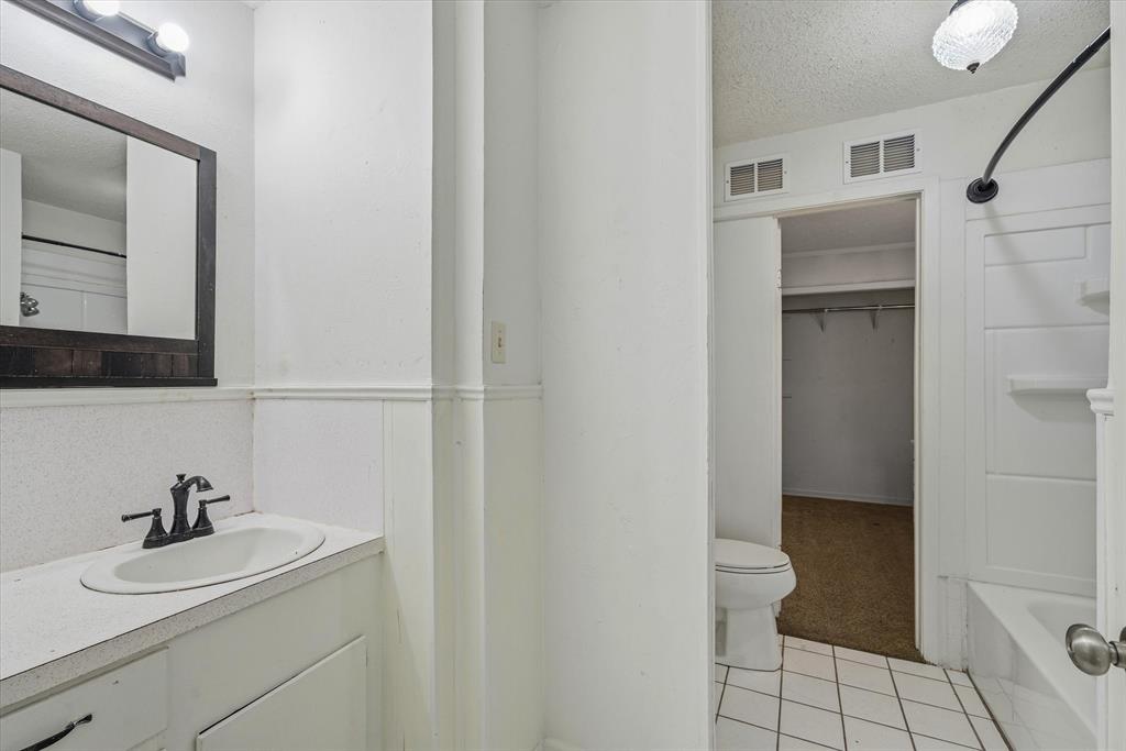 1729 Elliot Drive Canton, TX 75103 - Photo 20 of 40 Full bath featuring a textured ceiling, vanity, light tile patterned floors, a walk in closet, and shower / bath combination
