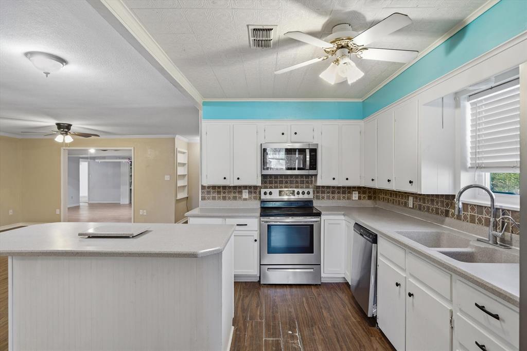 1729 Elliot Drive Canton, TX 75103 - Photo 9 of 40 Kitchen with a ceiling fan, stainless steel appliances, dark wood-style floors, a kitchen island, and white cabinetry