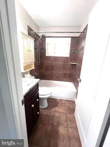a bathroom with a sink a toilet a window and tub