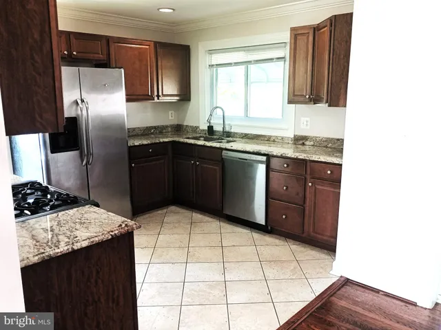a kitchen with stainless steel appliances kitchen island granite countertop a sink stove and refrigerator