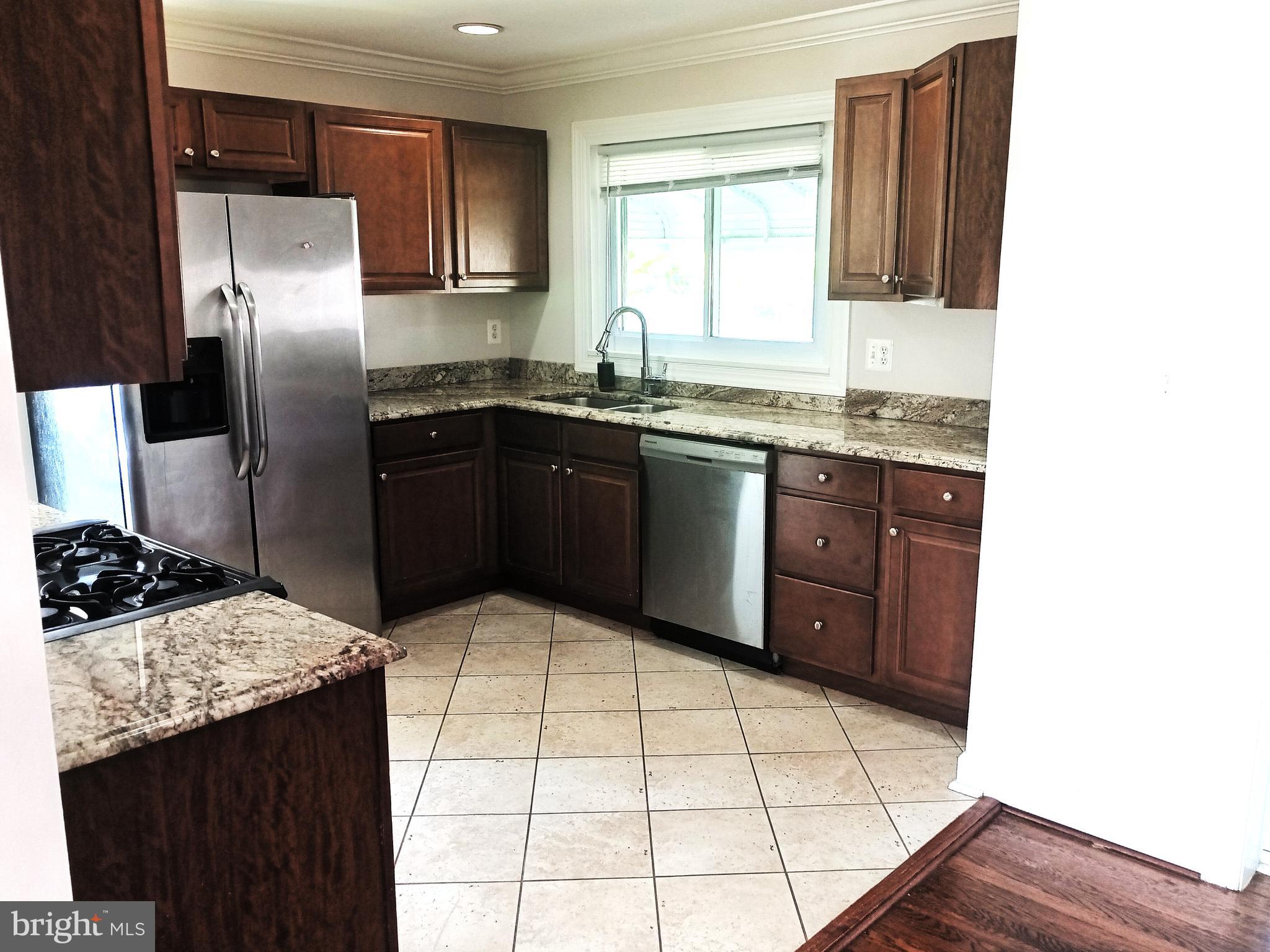 908 Vanderwood Road Catonsville, MD 21228 - Photo 10 of 36 a kitchen with stainless steel appliances kitchen island granite countertop a sink stove and refrigerator