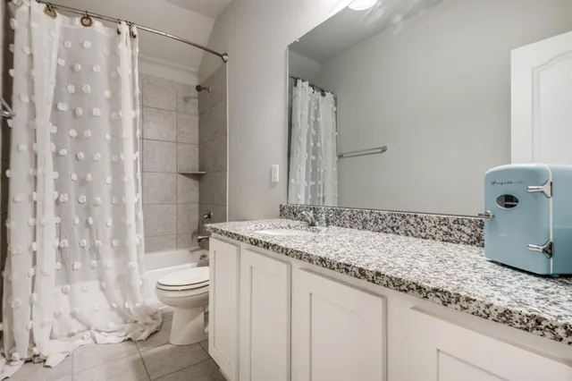a bathroom with a granite countertop sink a toilet and shower