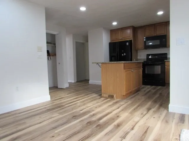 a view of kitchen with stainless steel appliances granite countertop a refrigerator a stove and a wooden floors