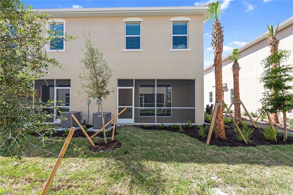 2856 Citrus Street Naples, FL 34120 - Photo 18 of 20 Rear view of house featuring a sunroom, stucco siding, and a lawn