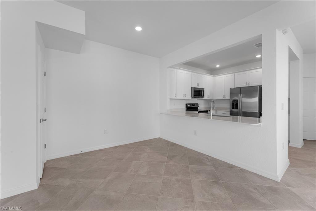 2856 Citrus Street Naples, FL 34120 - Photo 3 of 20 Kitchen with white cabinetry, appliances with stainless steel finishes, recessed lighting, a peninsula, and light stone counters
